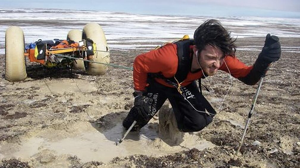 guy pulling sled through mud