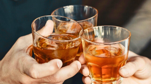 Three people making a toast with glasses of drink