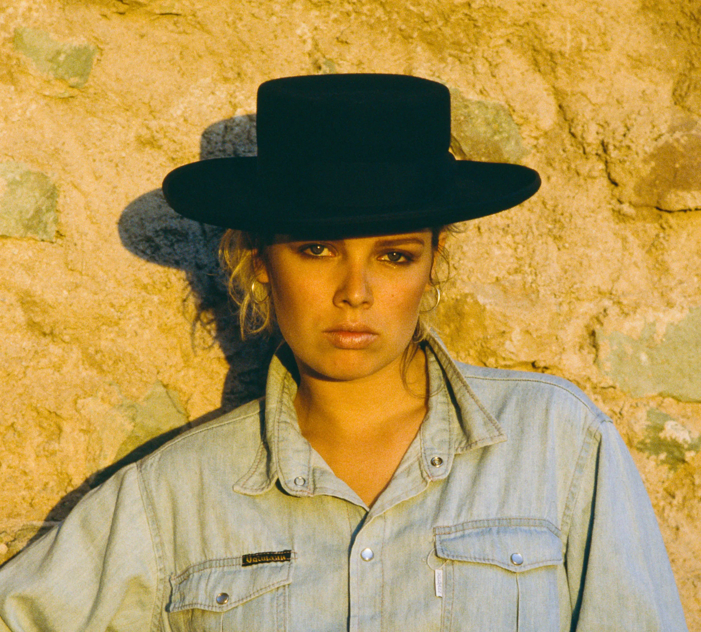 English pop singer Kim Wilde in a black hat and denim shirt.