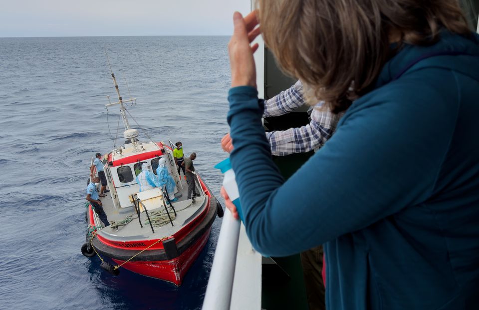 Passengers on the hantavirus-stricken cruise ship, MV Hondius, watch epidemiologists board the boat in Praia, during their voyage to Tenerife (AP)