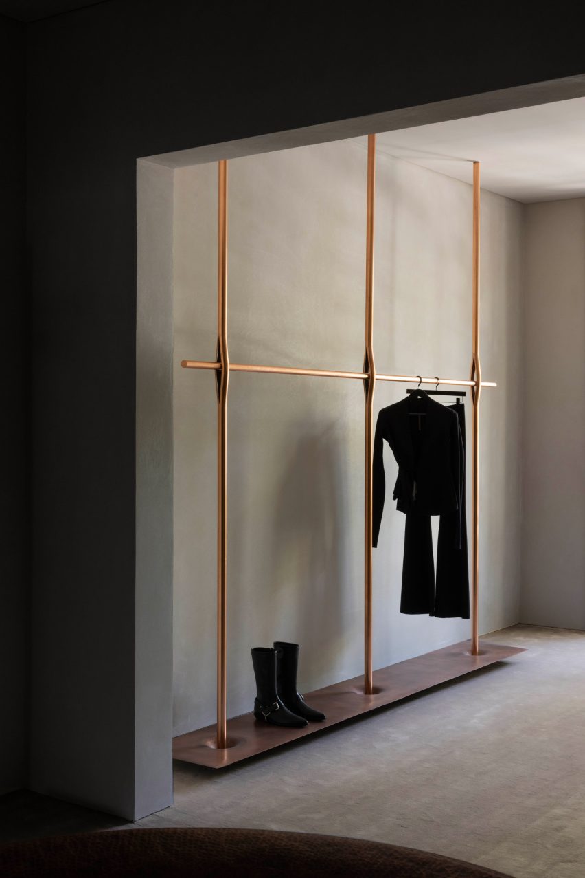 A horizontal copper rod splices vertical poles to create a garment rail