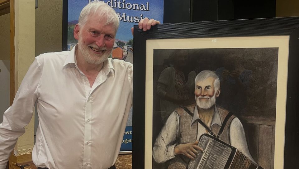 Charlie Harris posing with a portrait of himself after being honoured at the Feakle Traditional Music Festival. Image: Feakle Traditional Music Festival via Facebook
