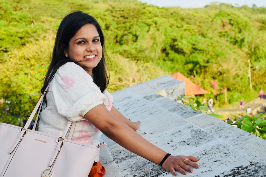 A woman smiles for the camera on a hill overlooking a small village.