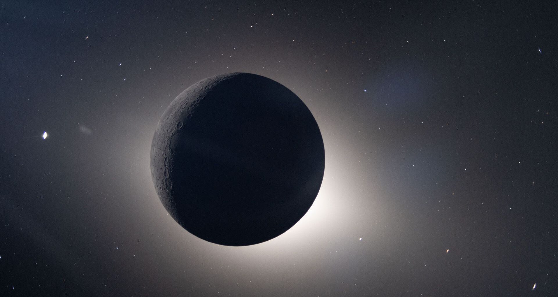 An image of the dark sphere of the moon in space as it blocks the sun, with a glowing sphere of light behind it.