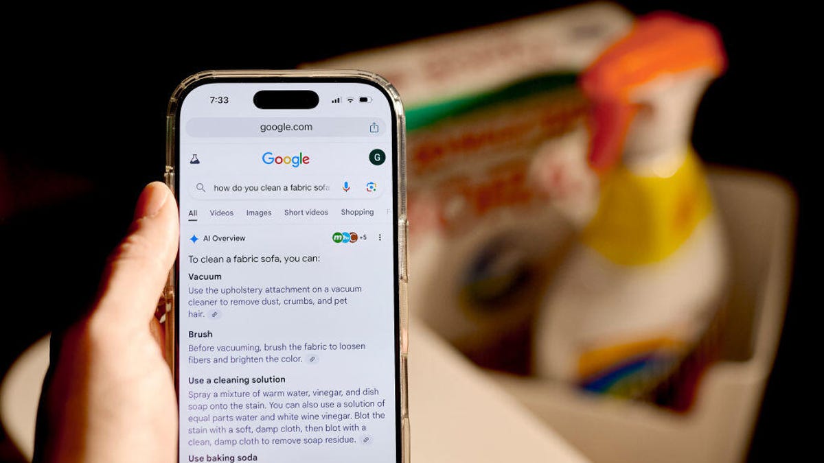 A phone displaying a Google Search AI summary for how to clean in front of cleaning supplies