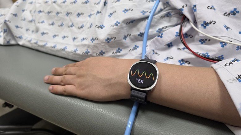 Samsung Watch shown worn by a patient in a hospital bed with tubes and wires around their body