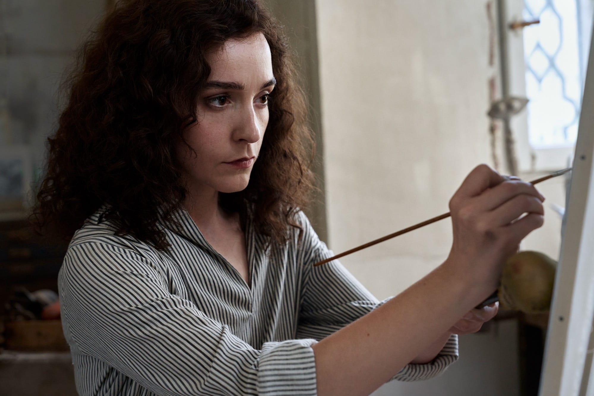 a white woman with dark curly hair painting