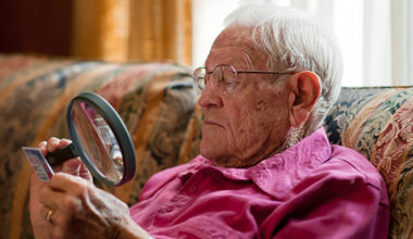 Elderly man looking at object with magnifier