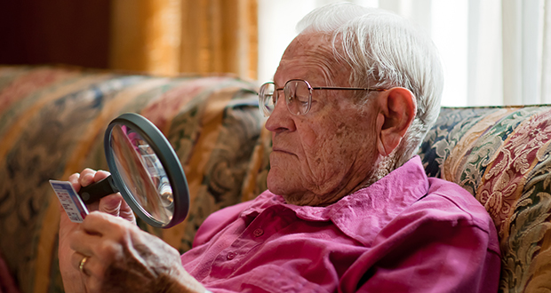 Elderly man looking at object with magnifier