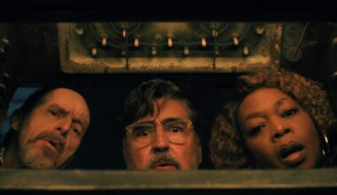 Two older white men and an older Black woman peer into something, curiously.