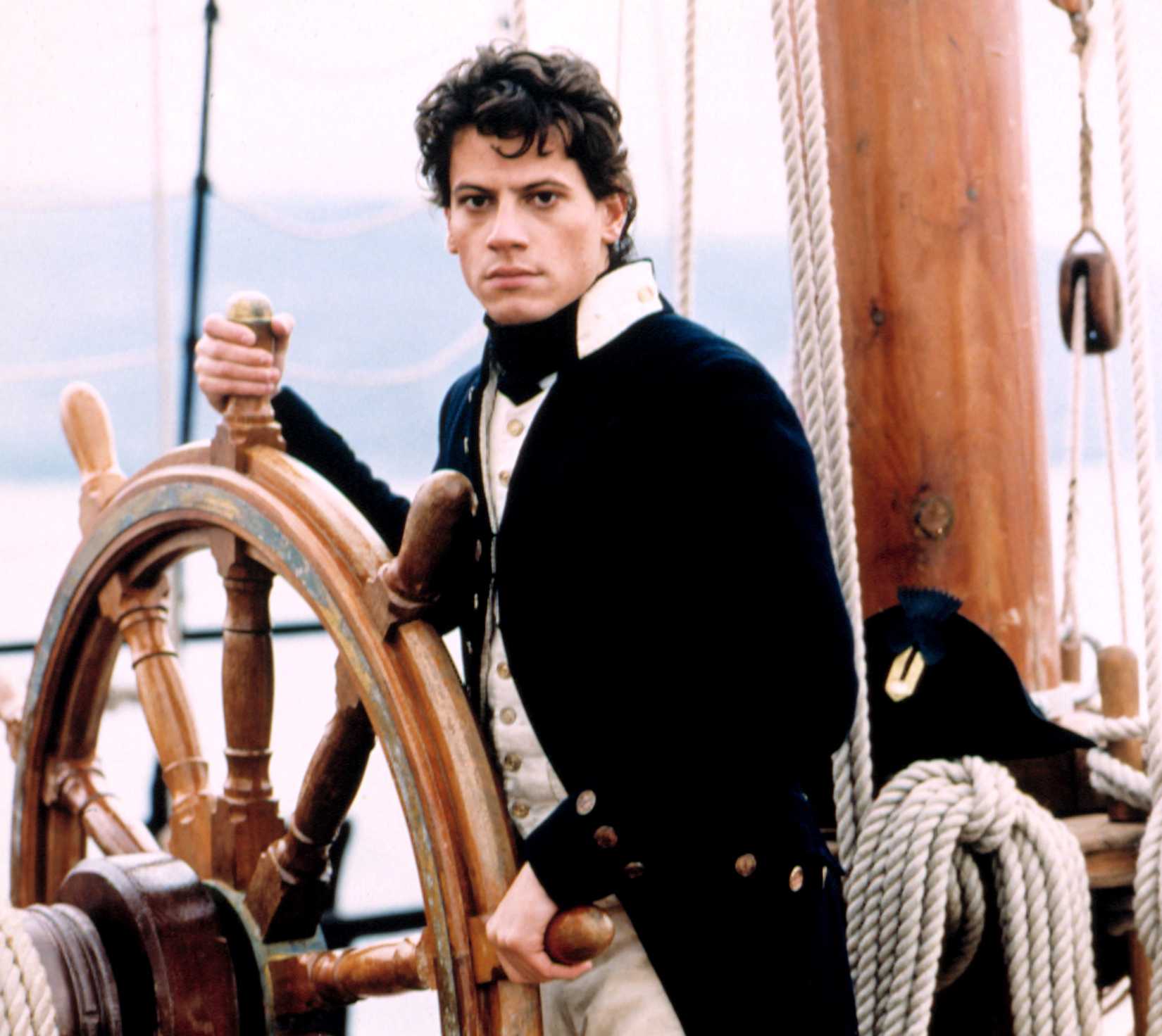 Ioan Gruffudd as Lieutenant Horatio Hornblower, a young, pale man in a British Navy uniform, at the wheel of a ship, in A&E Network's  Horatio Hornblower series