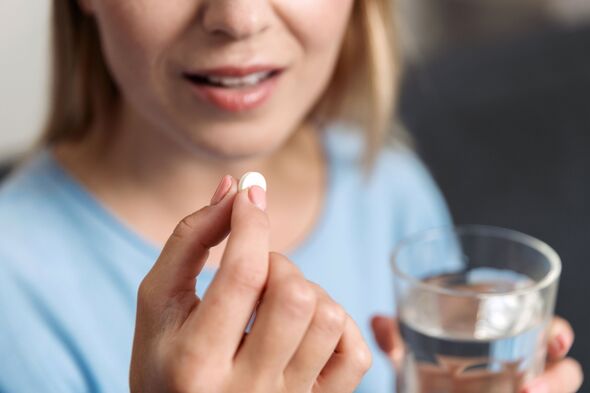 Young woman holds white pill and glass of water to take medication at home Young woman holds white pill and glass of water to take medication at home