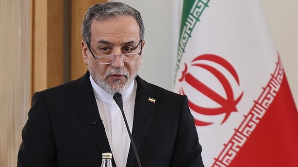 Iranian Foreign Minister Abbas Araghchi stands in front of an Iranian flag.