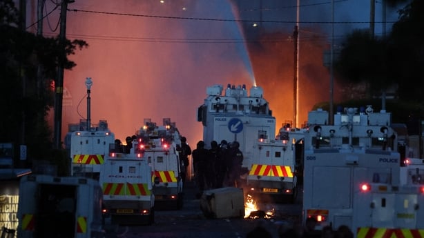 Rioters have set fire to wheelie bins and removed a garden fence to use as a shield against a police water cannon on Antrim Road