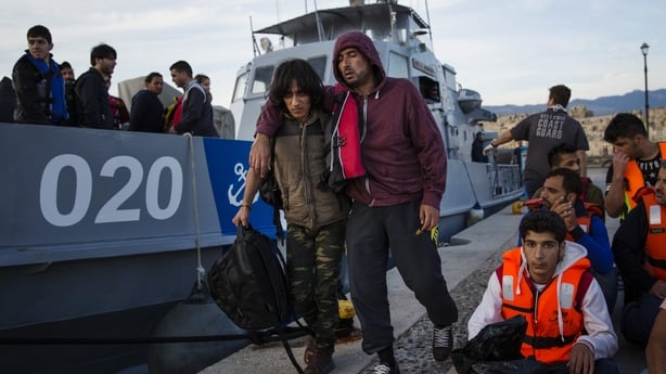 A migrant man is escorted to an ambulance after being picked up in a dinghy