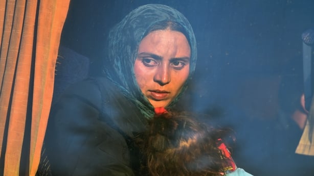 A mother and child pictured through the window of a bus