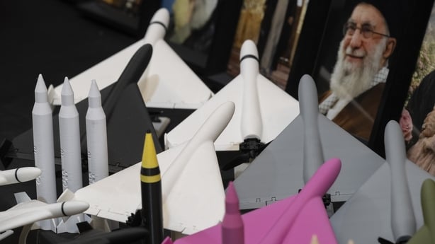 Scale models of Iran-made ballistic missiles and drones are placed in front of a portrait of Iran's late Supreme Leader Ayatollah Ali Khamenei 