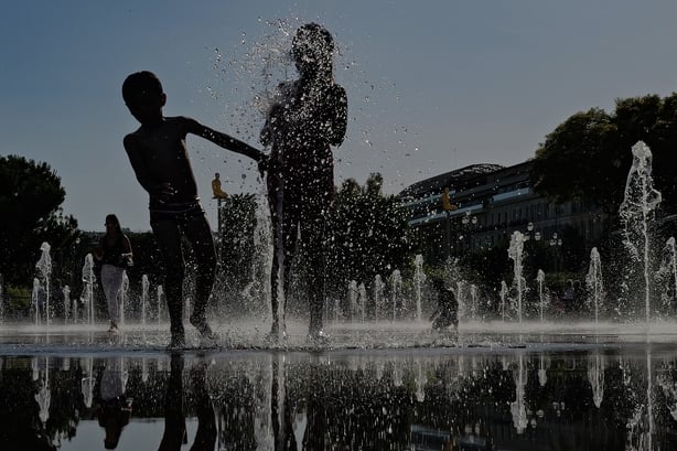 Children cool off in a water fountain during a heatwave in the French city of Nice