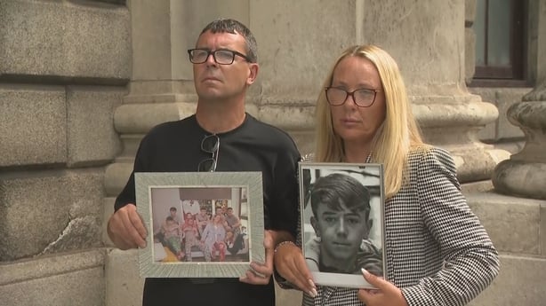 Parents of Killian Burnett outside court holding up family photos