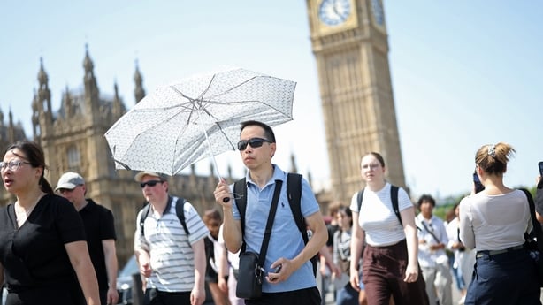 A man uses a parasol umbrella to shelter from the sun