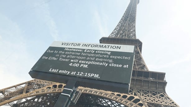 A low-angle shot of Eiffel Tower with a giant screen announcing its early closing due to heatwave in Paris