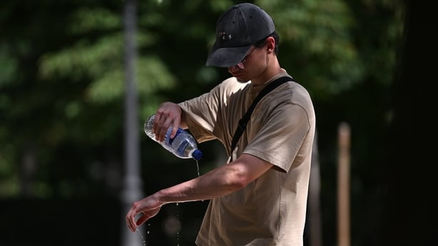 A man in a cap and t-shirt pours bottled water on his arm as temperatures soar above 40 degrees Celsius in Madrid, Spain, on June 23, 2026