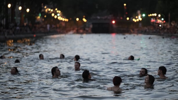 people are seen swimming in a canal in the evening time
