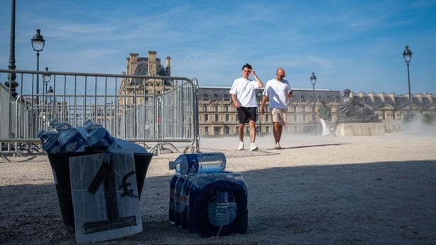 PARIS, FRANCE - JUNE 25: Bottled water is made available for sale as people walk through during an intense heatwave near the Louvre Museum on June 25, 2026 in Paris, France. Various European governments issued health warnings this week in relation to the high temperatures, which were nearing 40 degr