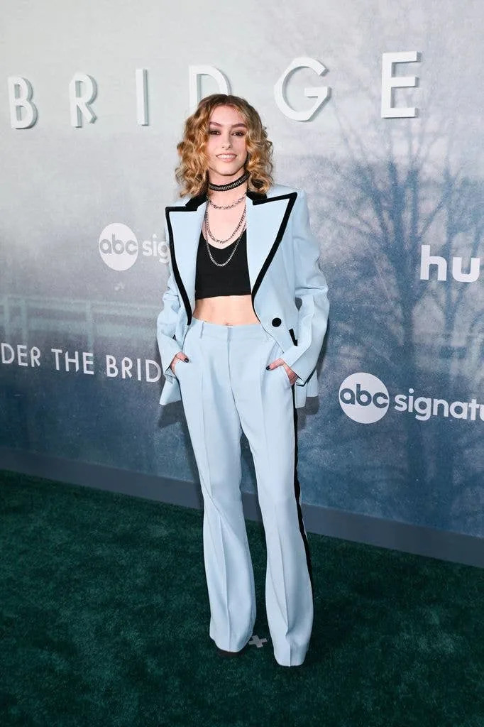 Ella Dixon in a blue suit with a large collar trimmed in black and a black cropped vest underneath.