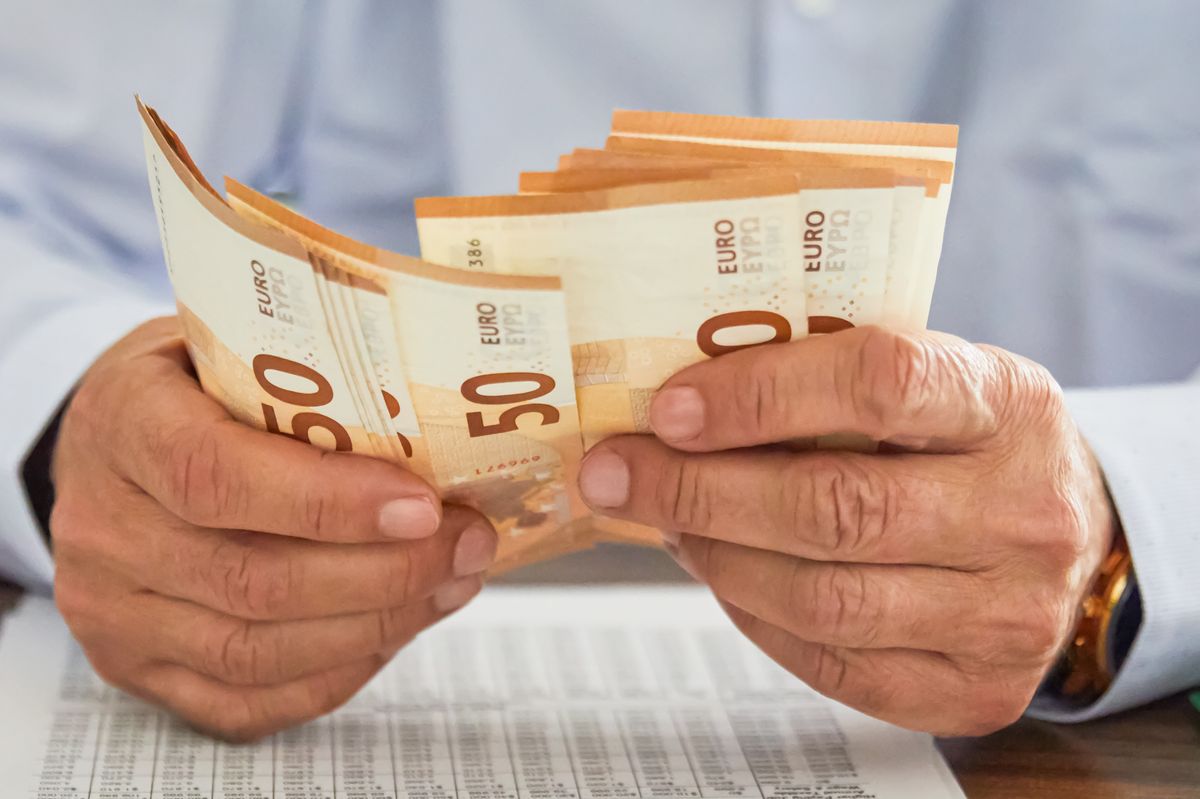 A close-up of hands handling a stack of Euro Banknotes representing cash transactions, savings, or financial management