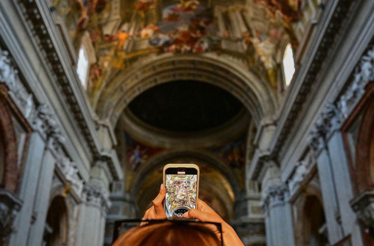 A young woman takes a picture of a ceiling fresco painting with a smartphone as she visits Church of St Ignatius of Loyola at Campus Martius in Rome on April 25, 2025.