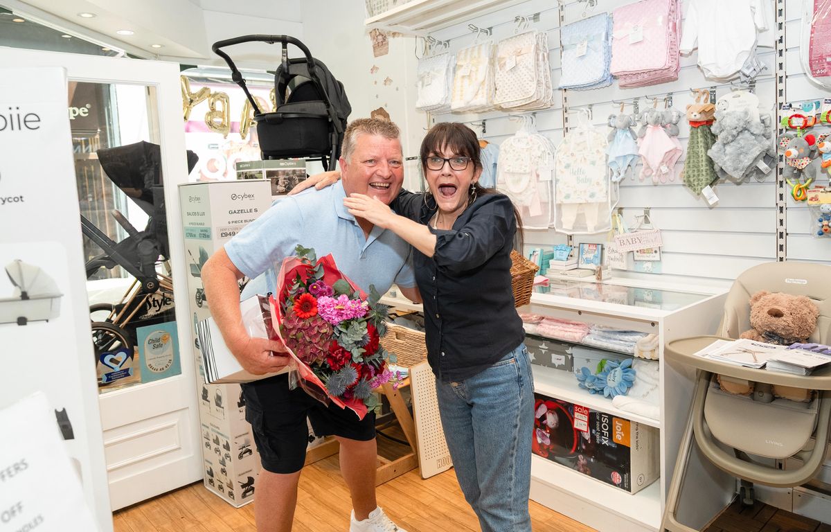 Gary MacDonald, who quit his job after scooping £5.2 million on the lottery, with Donna Samuels, during his visit to his former workplace to surprise old colleagues with flower bouquets and Lotto lucky dip tickets.