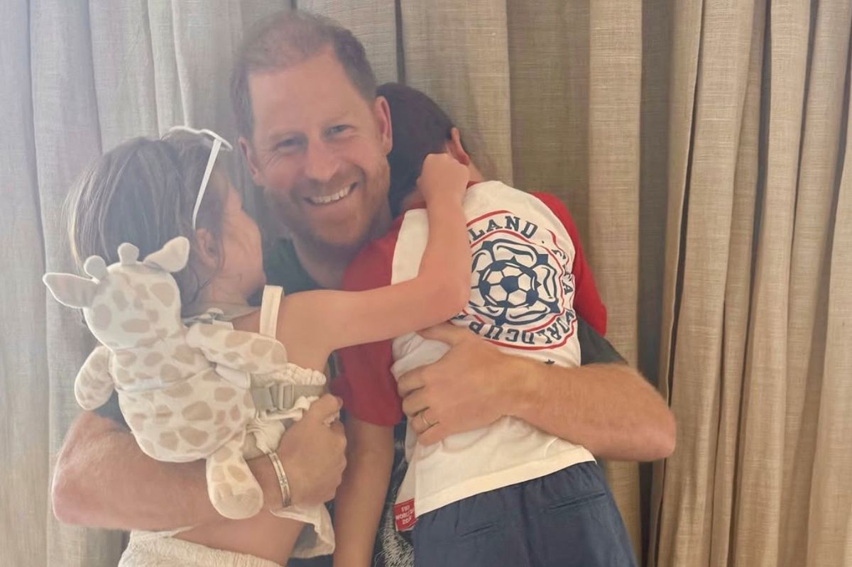 Prince Harry smiling and hugging his two children