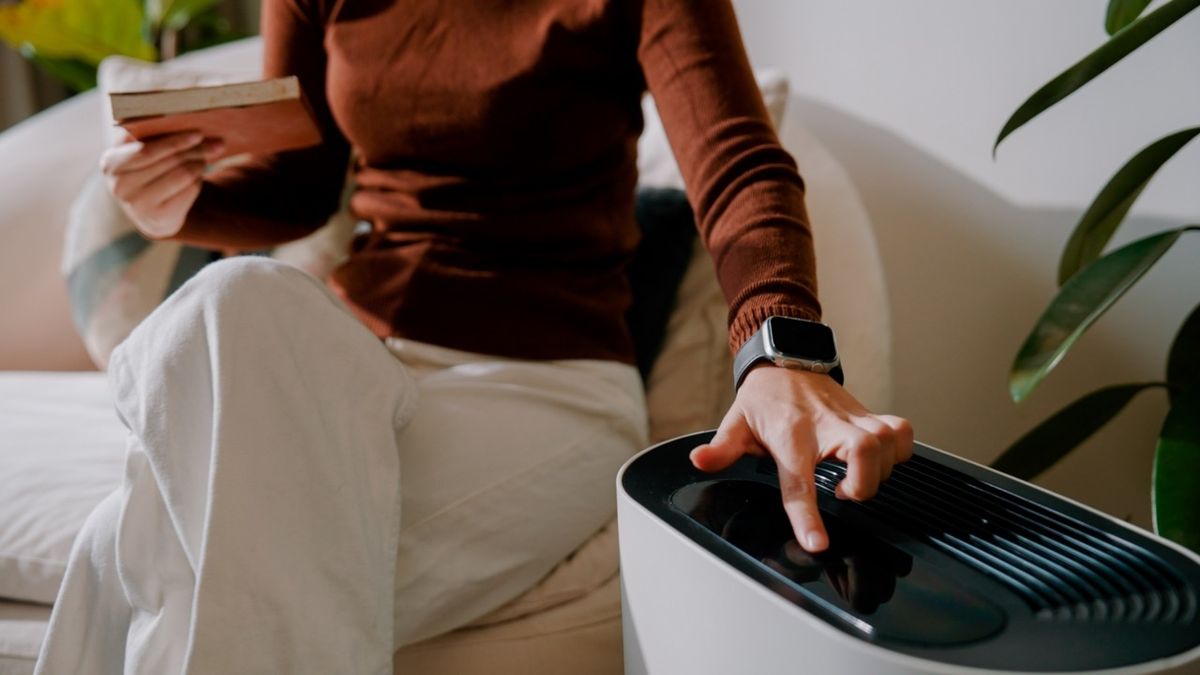 A closed-up view of a woman turning on an air purifier
