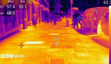 Thermal imaging photo showing a bright yellow pavement with darker, cooler figures walking along