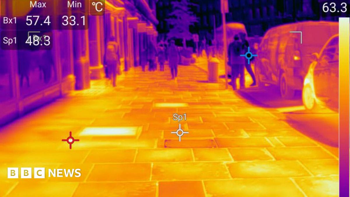 Thermal imaging photo showing a bright yellow pavement with darker, cooler figures walking along