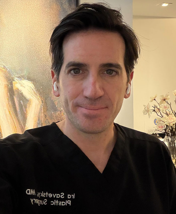Plastic surgeon wearing black scrubs with name tag in clinic setting