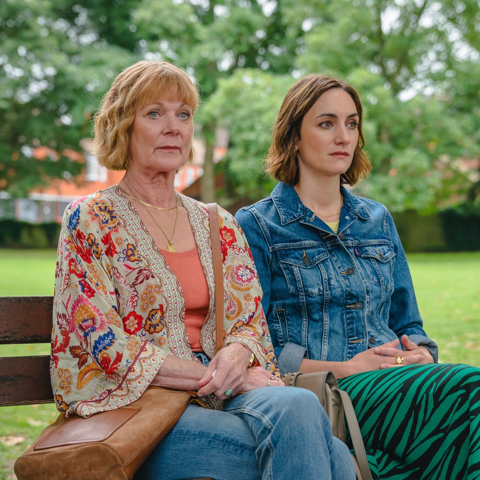 two women sitting on a bench in a park