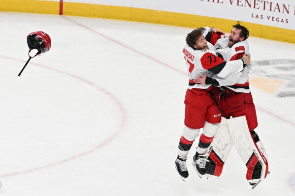 Carolina Hurricanes left wing Mark Jankowski (77) and goaltender Brandon Bussi (32) celebrate after a win over the Vegas Golden Knights in Game 6 of the NHL hockey Stanley Cup Final series, Sunday, June 14, 2026, in Las Vegas. (AP Photo/Candice Ward)