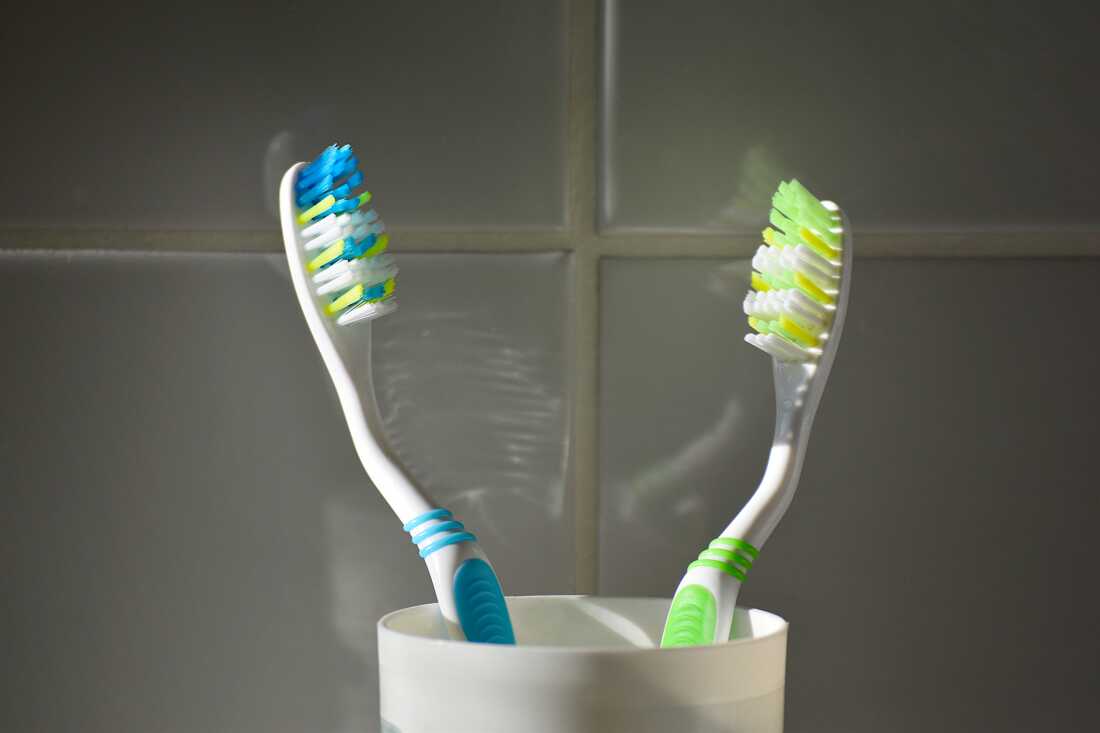 2 toothbrushes in a plastic glass in close up