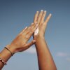 Close-up of hands applying sun cream under a bright blue sky in Maldives