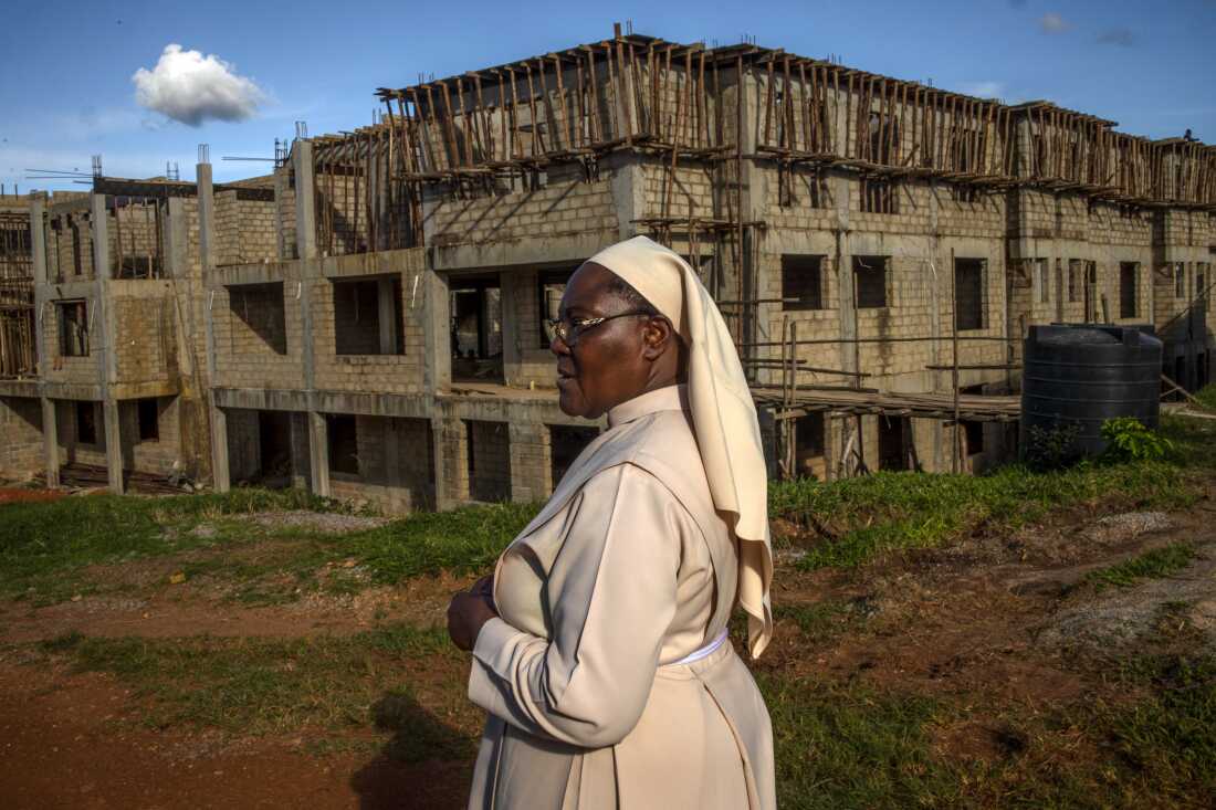 Sister Jean Francis stands outside the Little Sisters of St. Francis premises in Nkokonjeru, Uganda, on May 11, 2026, in front of a newly constructed building intended to support the congregation’s growing needs, including care for retired sisters. After more than 25 years working in healthcare, Sister Jean Francis helped advocate for a partnership between the Little Sisters of St. Francis and the African Palliative Care Association to improve end-of-life care for aging nuns in Uganda. The pilot program seeks to address the lack of support many retired sisters face after decades spent serving communities through schools, clinics, and religious work.