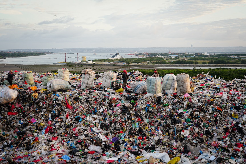 A close up of a pile of trash made of plastic bags and other disposed household items.
