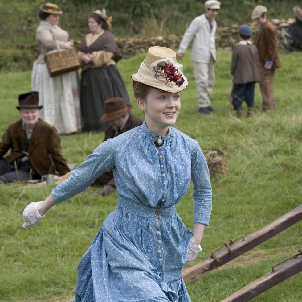 group of people in historical attire engaged in activities on a grassy field