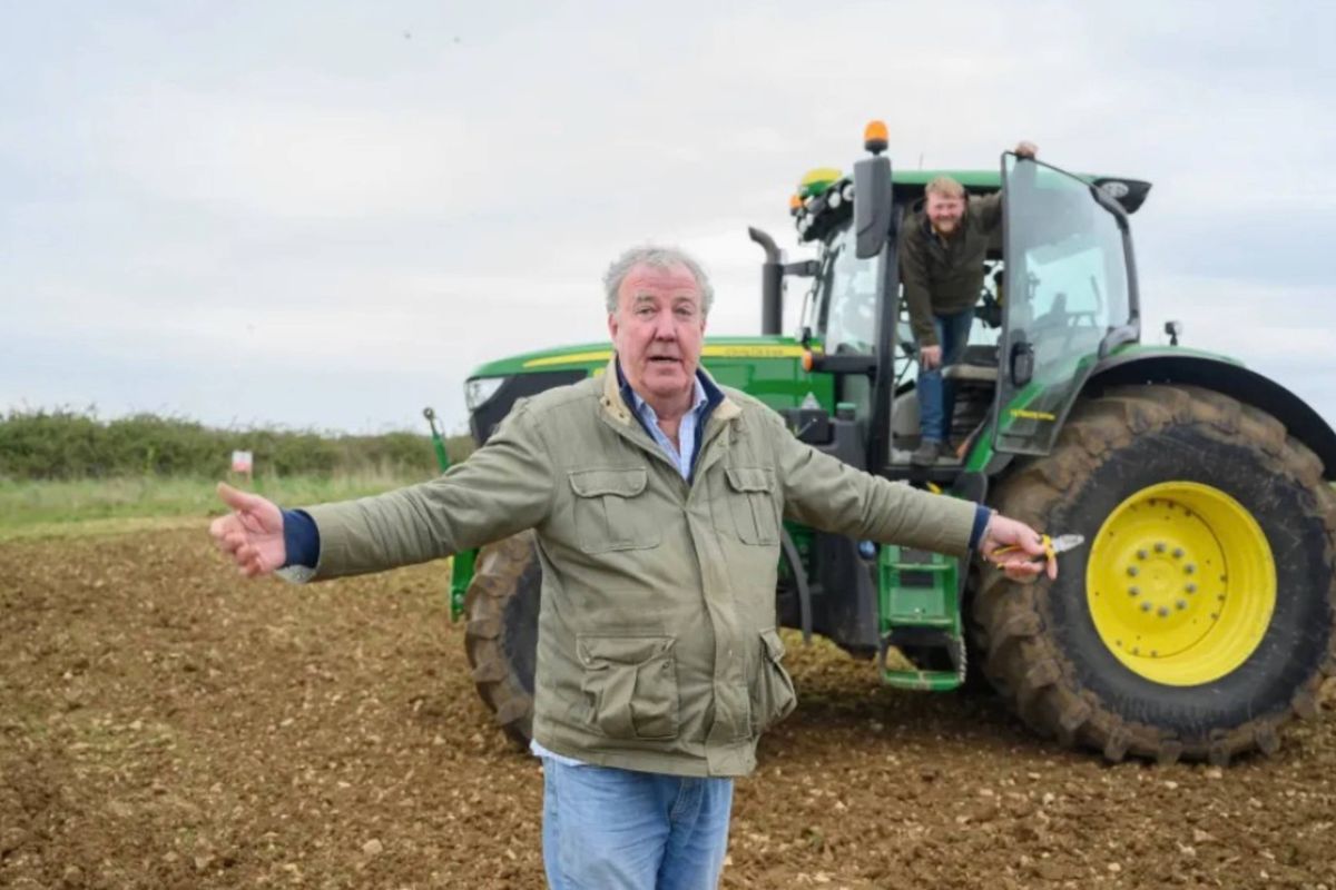 A man stands in front of a tractor