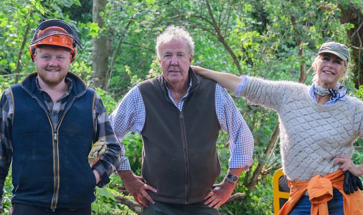 Two men and a woman stand together in a forest