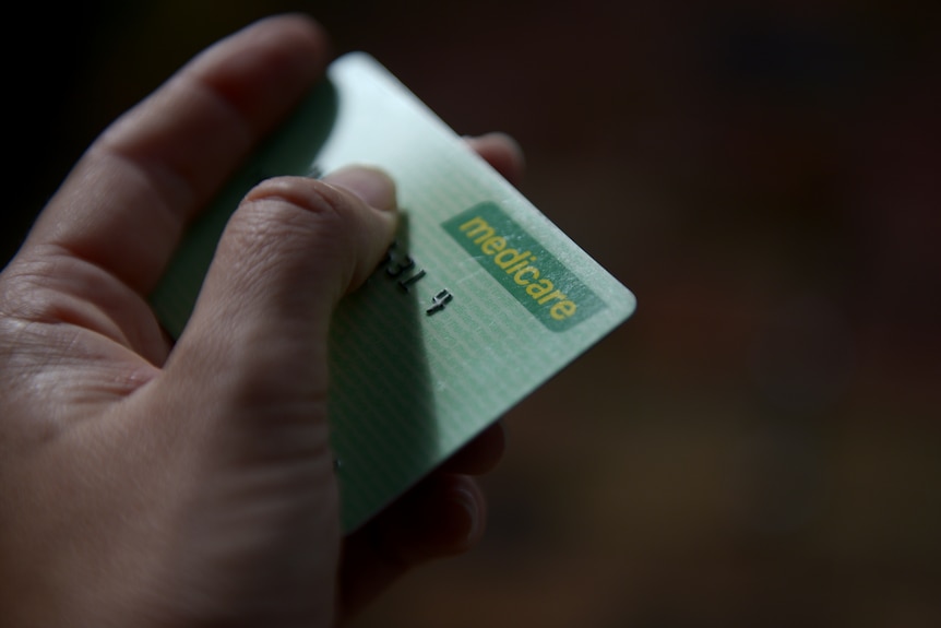 A hand holds a medicare card.