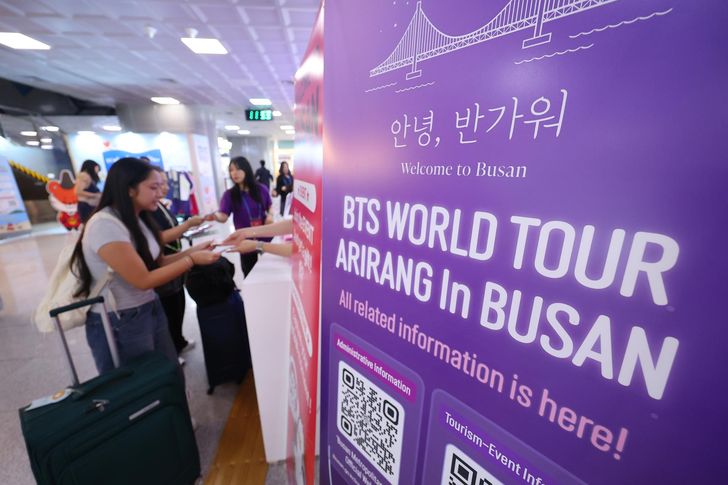 BTS fans from around the world receive souvenirs at a welcome booth set up by the Busan Tourism Organization in the international arrivals hall of Gimhae International Airport in Busan, June 10. Yonhap