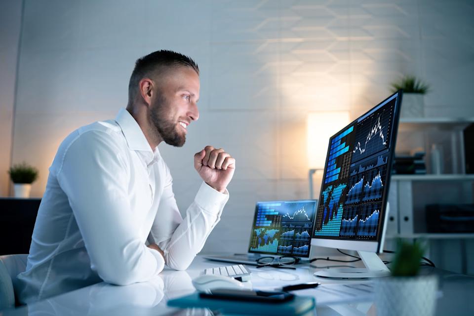 An analyst studying stock charts on multiple monitors.