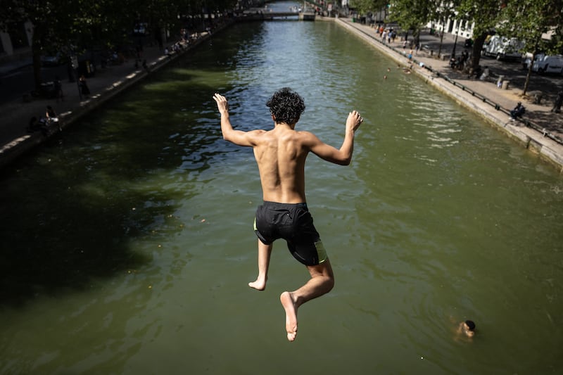 People jump into Canal Saint-Martin in Paris on Thursday. Photo: Simon Wohlfahrt/AFP via Getty Images